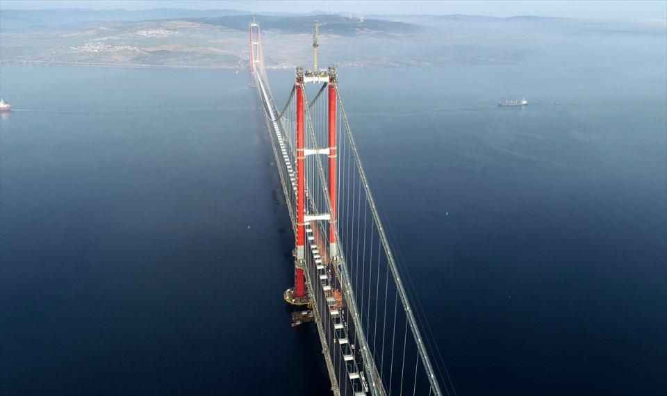 <p><span>Ana kablo imalatları kapsamında orta açıklıklarda 288, yan açıklıklarda ilave 16 kablo demeti ile toplam 304 kablo demetinden oluşan ana kablo montajı ile tabliyeleri ana kabloya bağlayan kelepçe ve askı halatı montaj çalışmaları da sonlandı. </span></p>