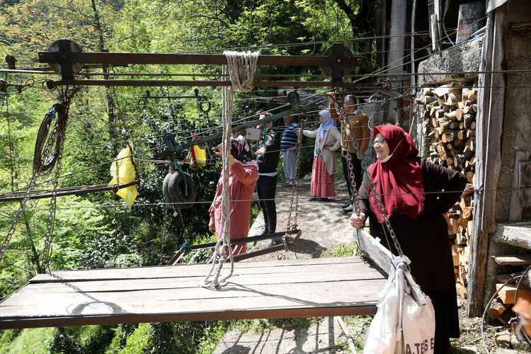 <p>Ulaşım sıkıntısı nedeniyle evlerini sürekli kullanamayan Sarı ailesi, 10 yıldır ev ve bahçelerine gitmek için sabahın erken saatlerinde yerden yüksekliği 300 ile 800 metre arasında değişen, 800 metre uzunluğundaki teleferiğe biniyor, işleri bittikten sonra akşam saatlerinde yeniden teleferikle geri dönüyor.</p>
<p>Bölgede arazisi bulunan 13 aile de ulaşım için aynı yolu kullanıyor.</p>
<h3>"Ölümüz de dirimiz de teleferikle"</h3>
<p>Meryem Sarı (73), 55 yıl önce gelin geldiğini, uzun yıllardır teleferiği ulaşım aracı olarak kullandığını anlattı.</p>