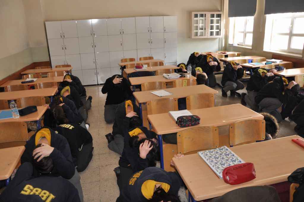 <div class="editorPart blackle" id="trtdty">
<p>Tatbikat kapsamında, mesajın duyulması halinde güvenli görülen bir yerde, sağlam bir nesnenin yanında ya da altında çökülecek. Sırt, pencerelere dönük şekilde kapanılacak, baş ve boyun, düşme ihtimali olan cisimlerden korunacak. Sarsıntı sona erene kadar, yatak veya oturma grubu gibi ağır ve büyük eşyalara tutunup beklenecek.</p>
<p></p>
<p><strong>KAYNAK: TRT HABER</strong></p>
</div>